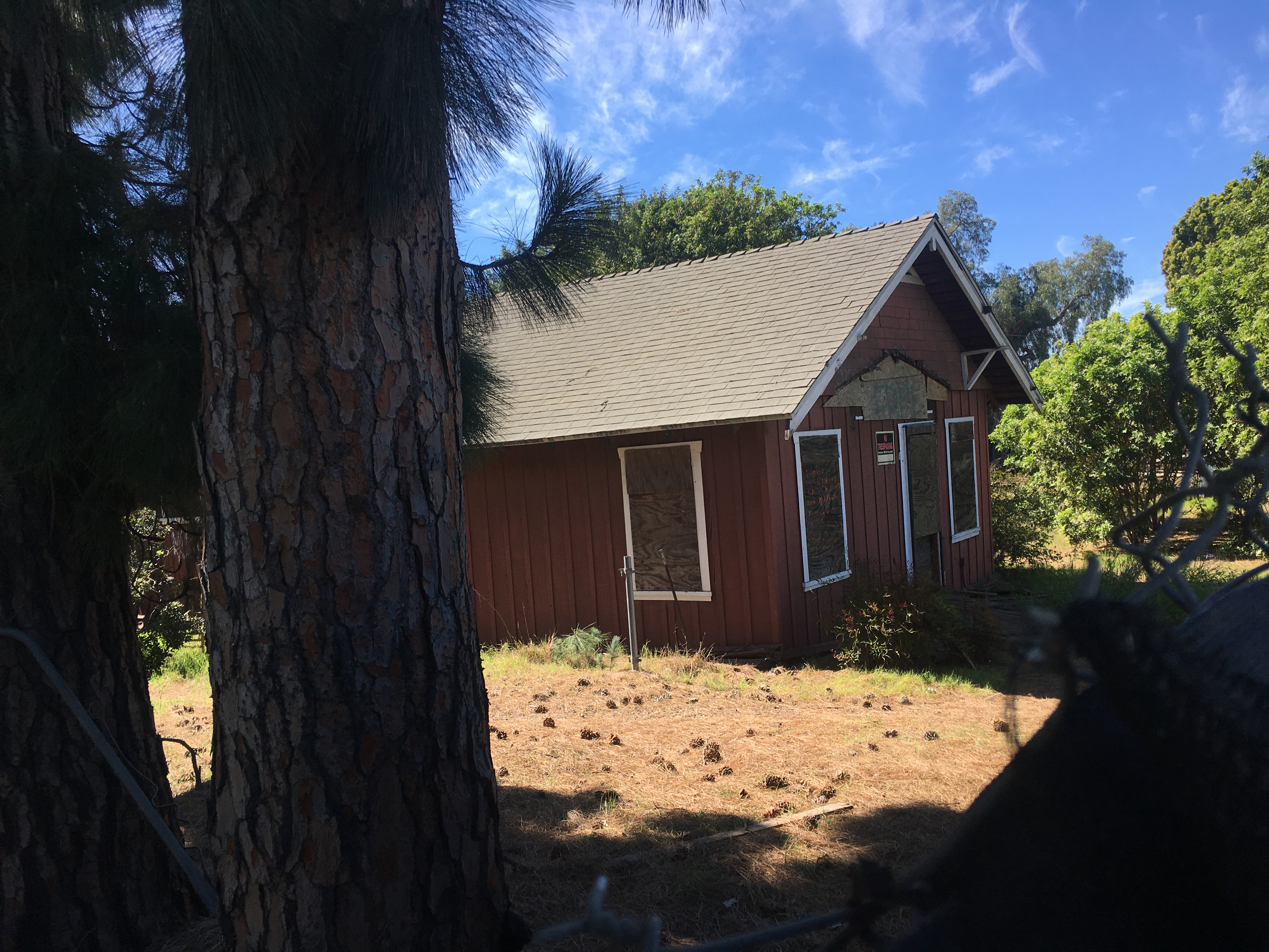 A picture of one of the original buildings of the Wintersburg Church, which has somewhat fallen apart. This building sits behind a long black tarp fence enclosing a couple acres of land. Not pictured here, another part of the Wintersburg Church burned down in February 2022.